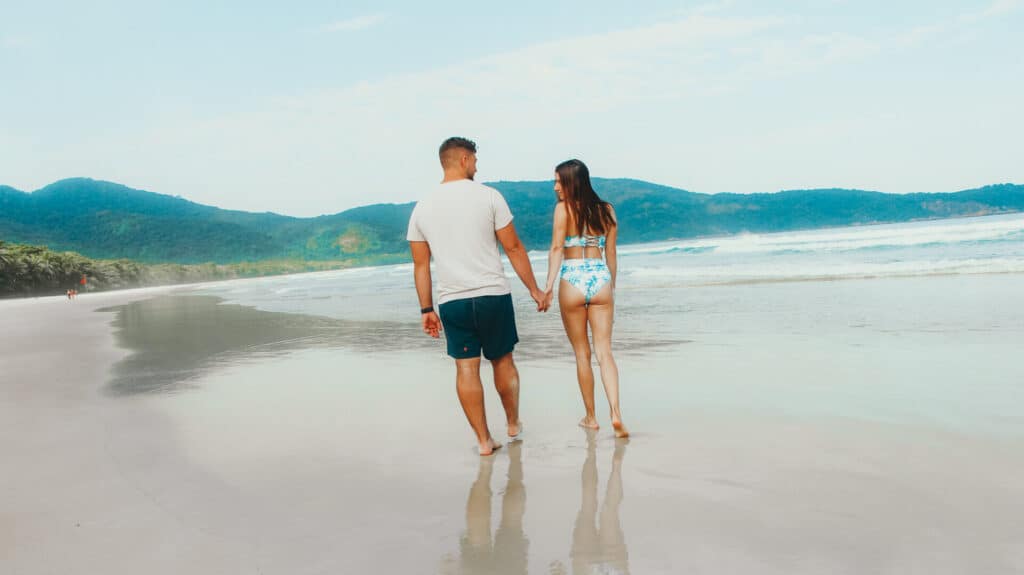 man and woman holding hands during walk on beach