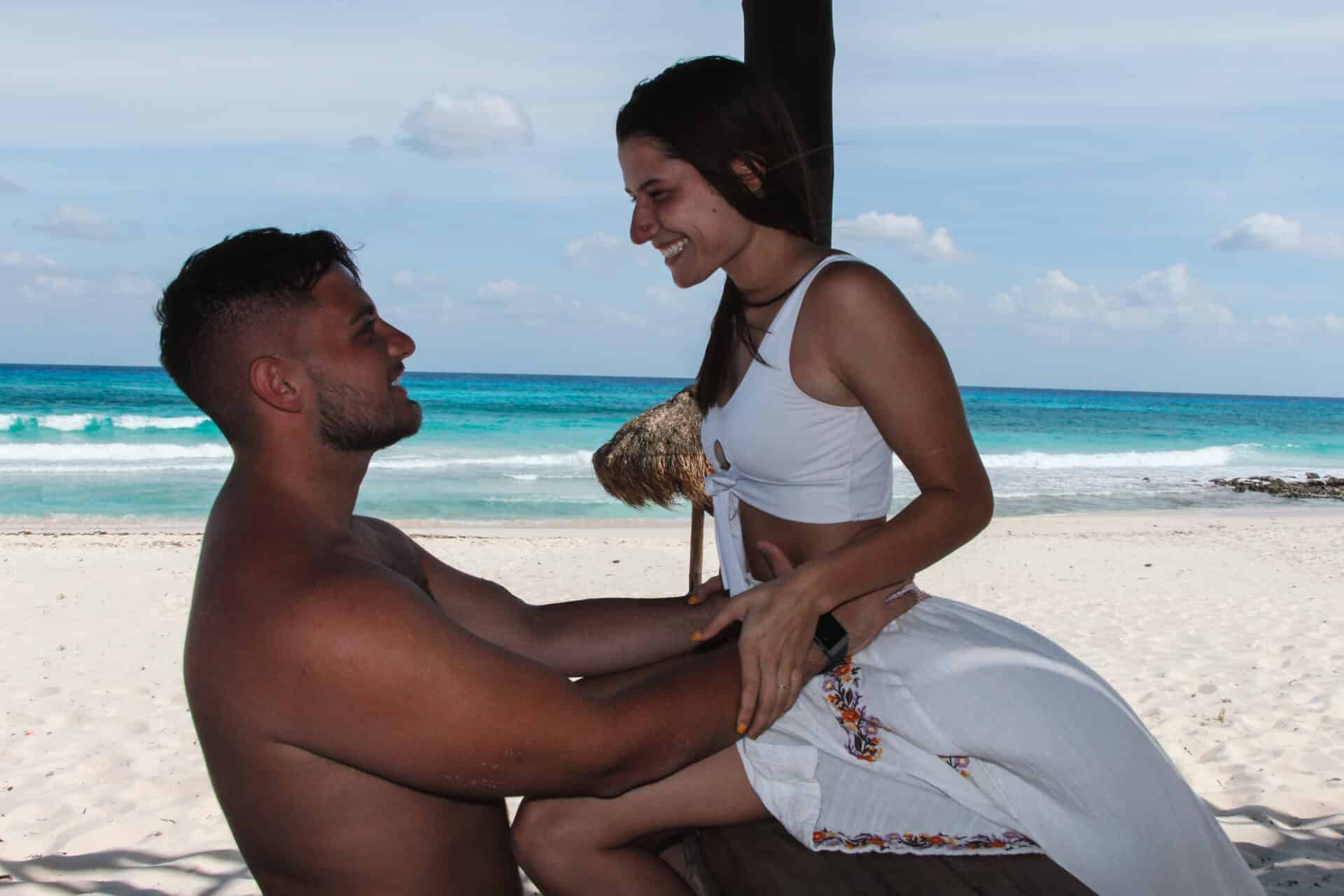 man embracing woman in flowing white skirt on white sand beach in cozumel