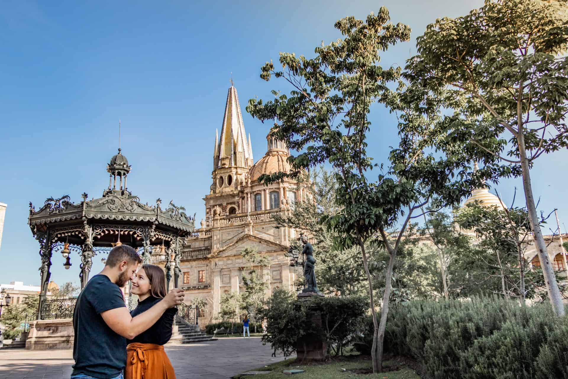couple in black dancing in front of mexican gondala and cathedral