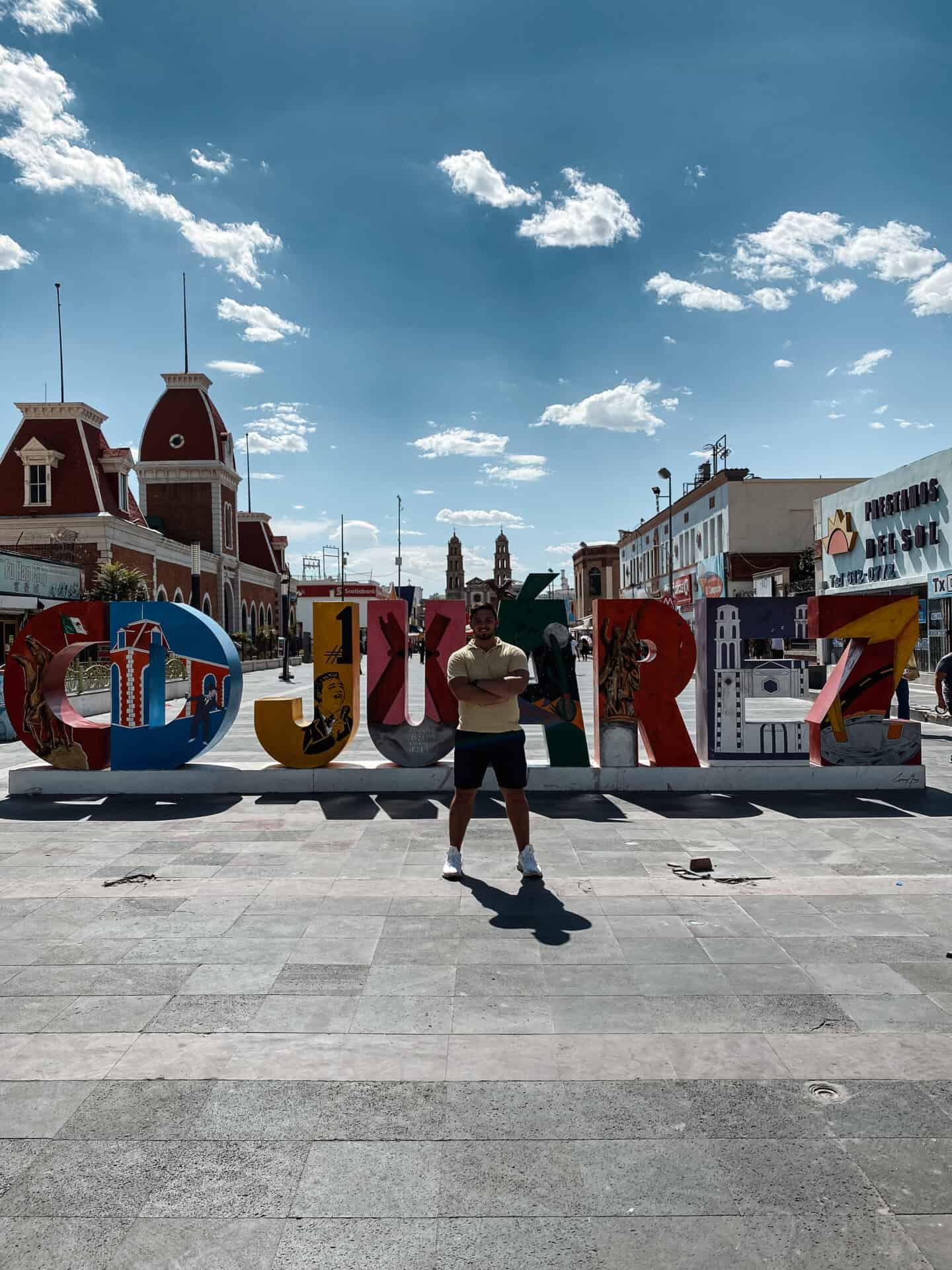 man standing in front of  colorful Juarez sign