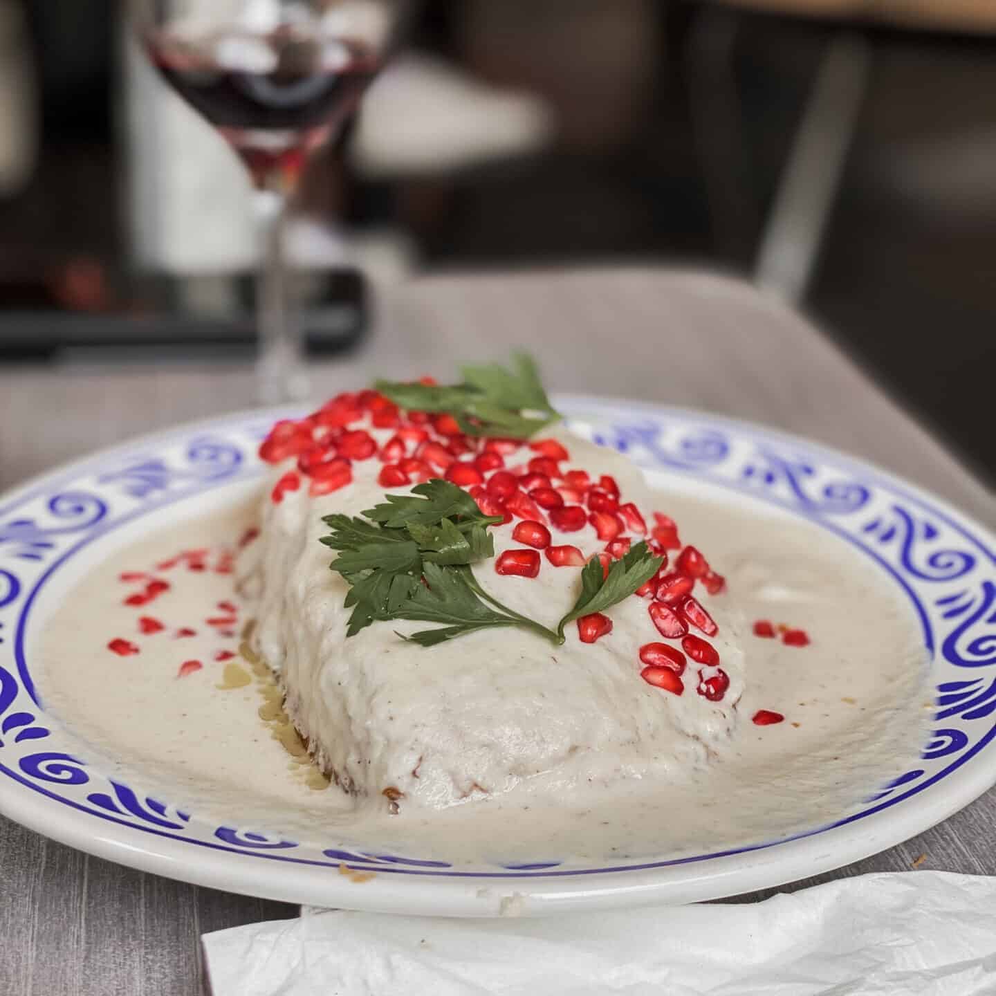 chiles en nogada in white sauce with pomegranate sprinkled on top