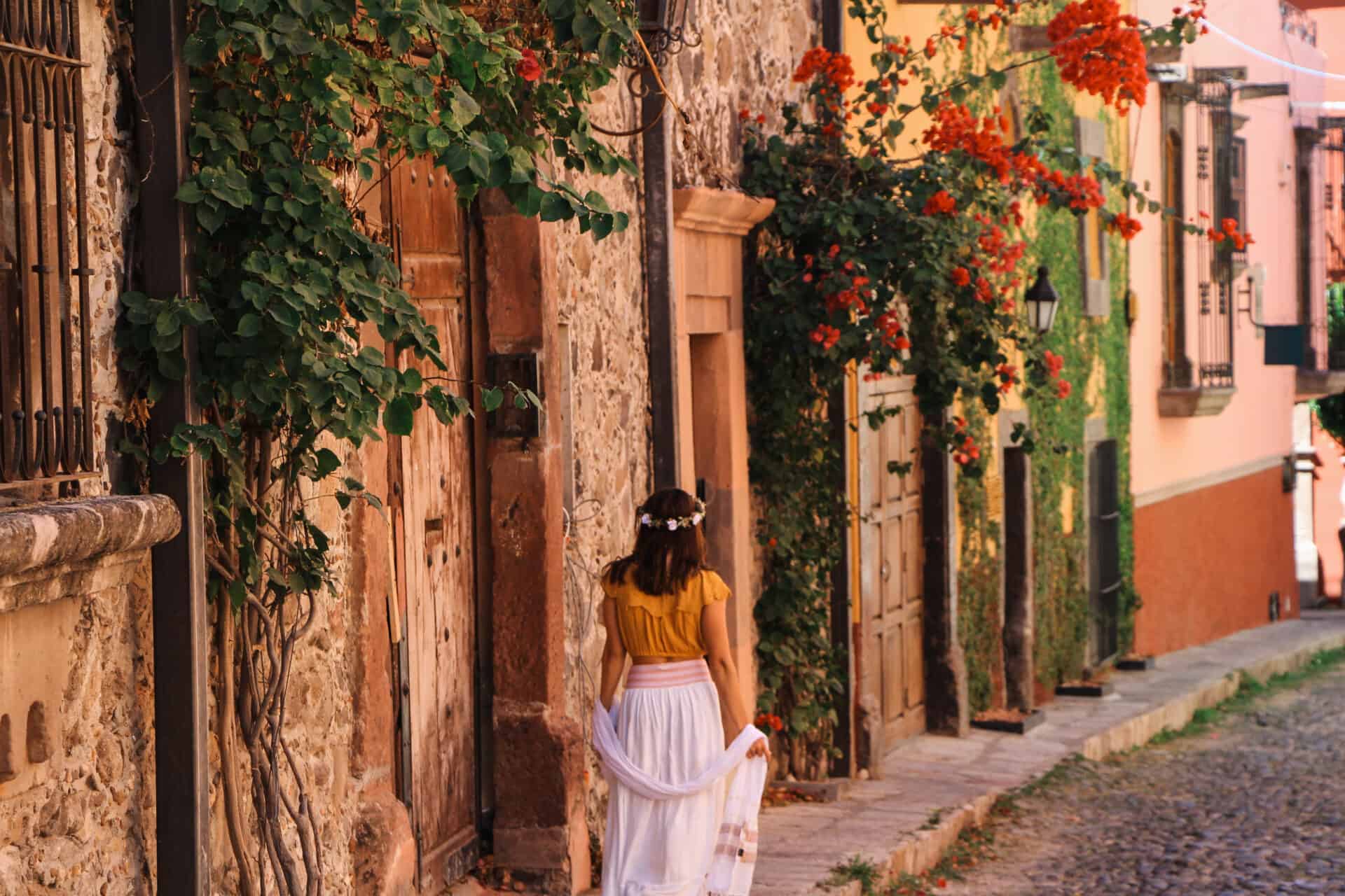 woman in yellow blouse and flowing white skirt walking the beautiful stone streets of san miguel de allende