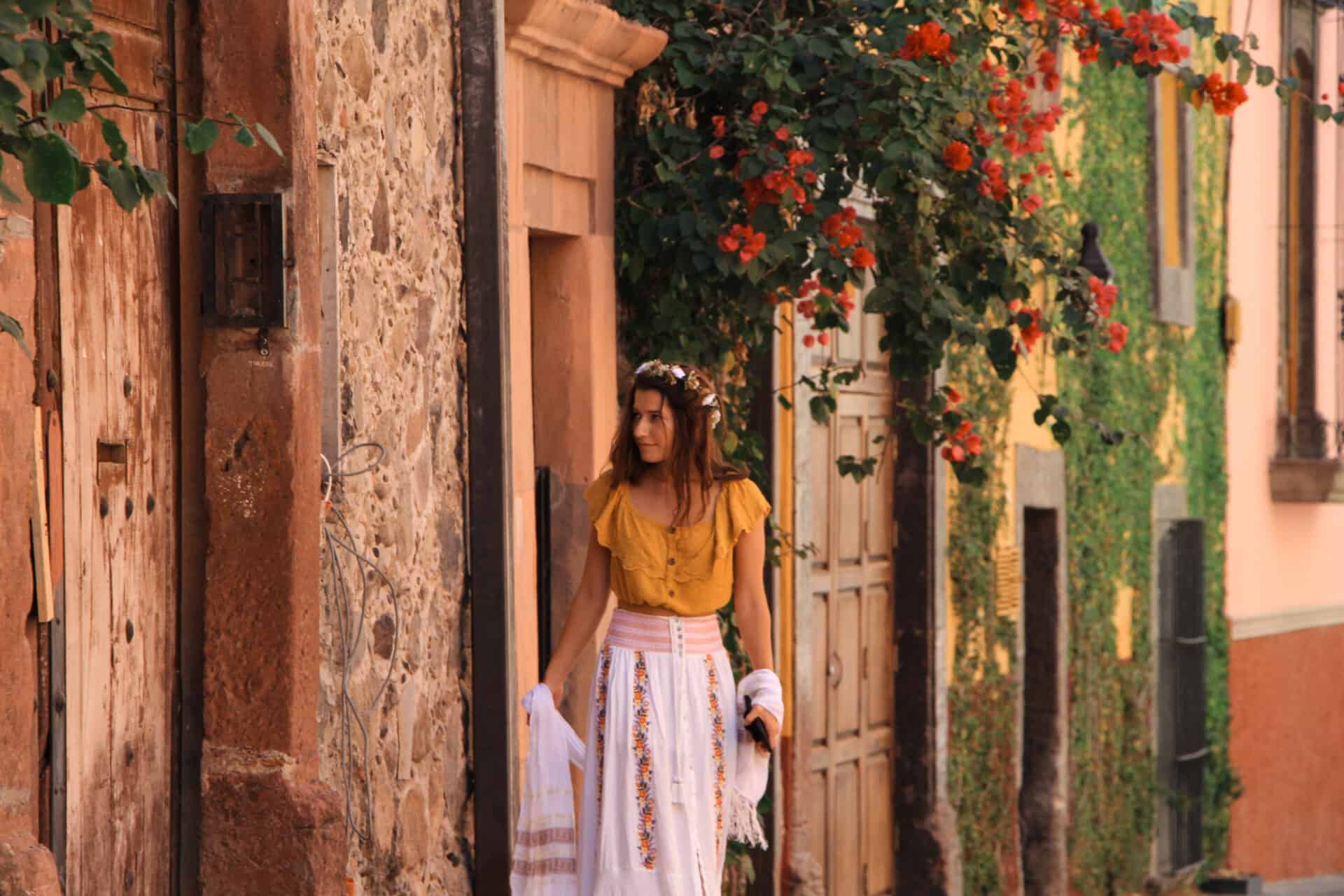 woman in yellow blouse and flowing white skirt walking the beautiful stone streets of san miguel de allende