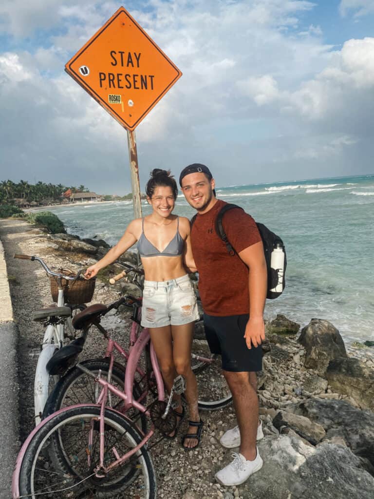 man and woman with bicycles standing in front of orange road sign