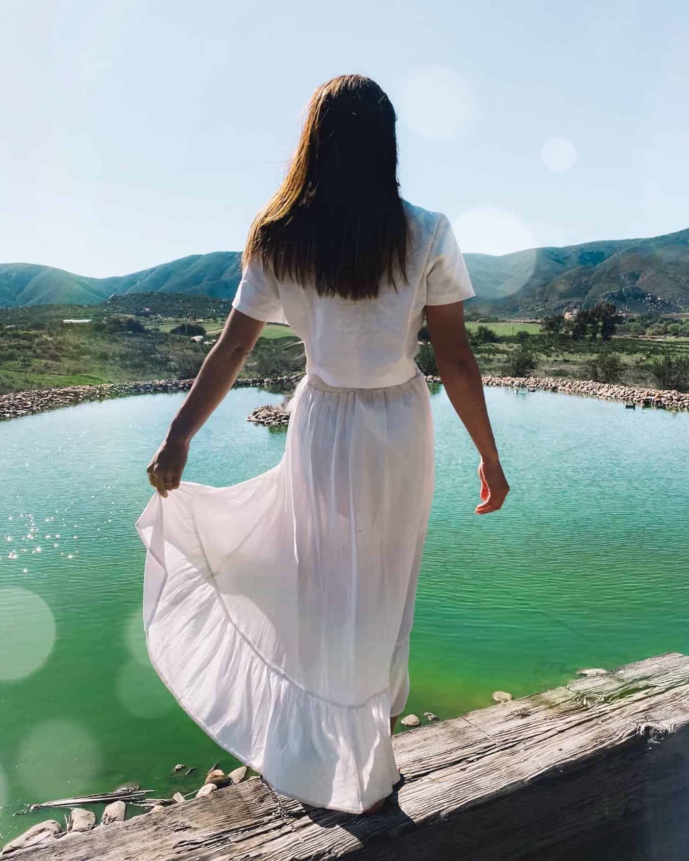 Woman in white dress above a green lake in Mexican wine country
