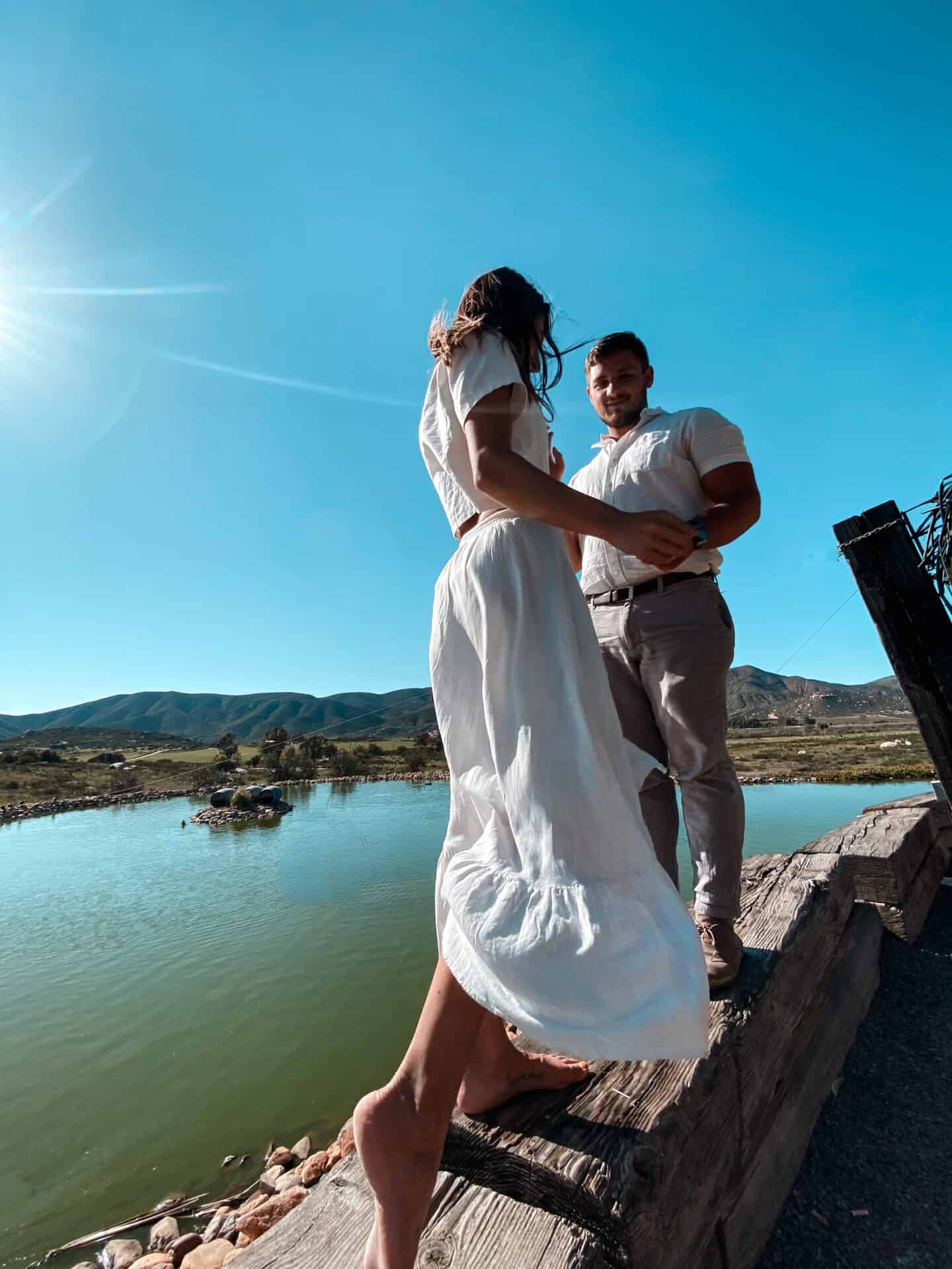 Woman in white dress and man above a green lake in Mexican wine country