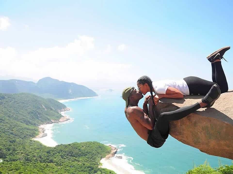 couple kissing and dangling off of cliff