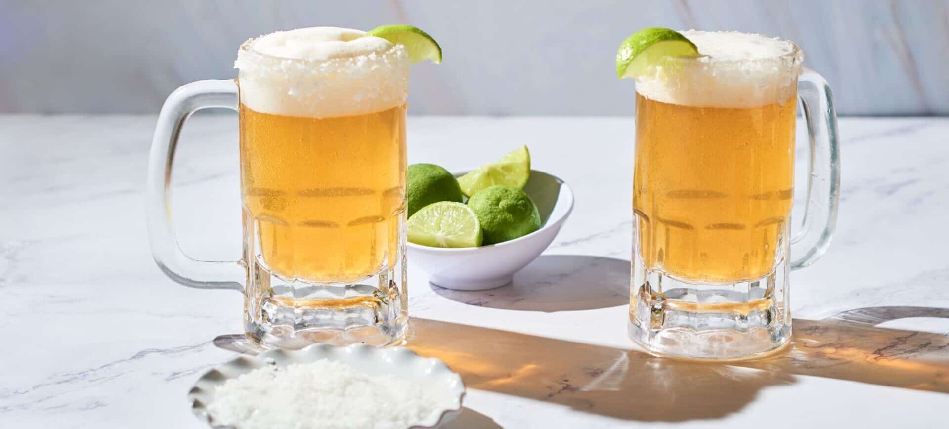 two glasses of yellow beer with limes and salt