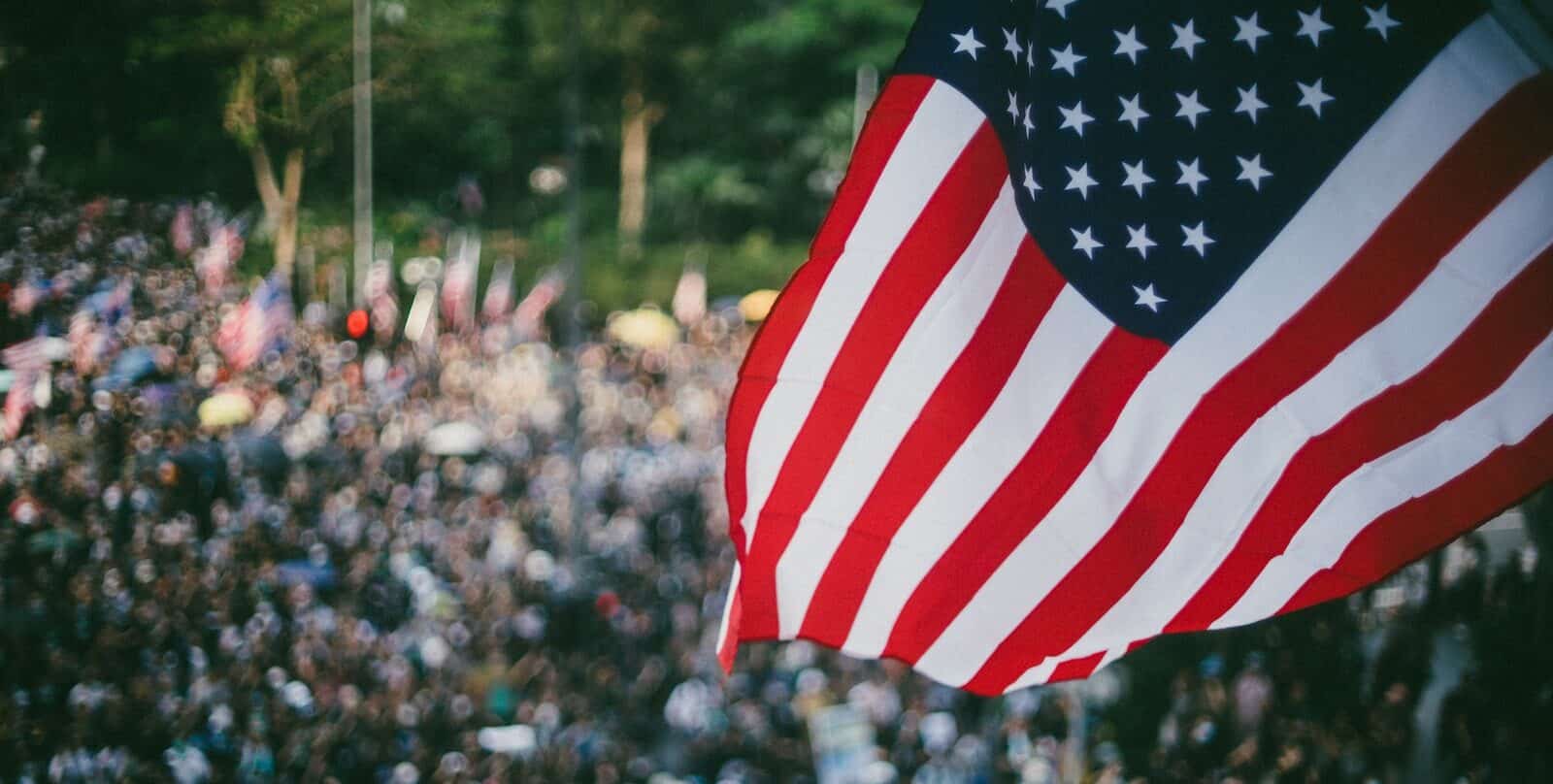 US flag waving over crowd of people