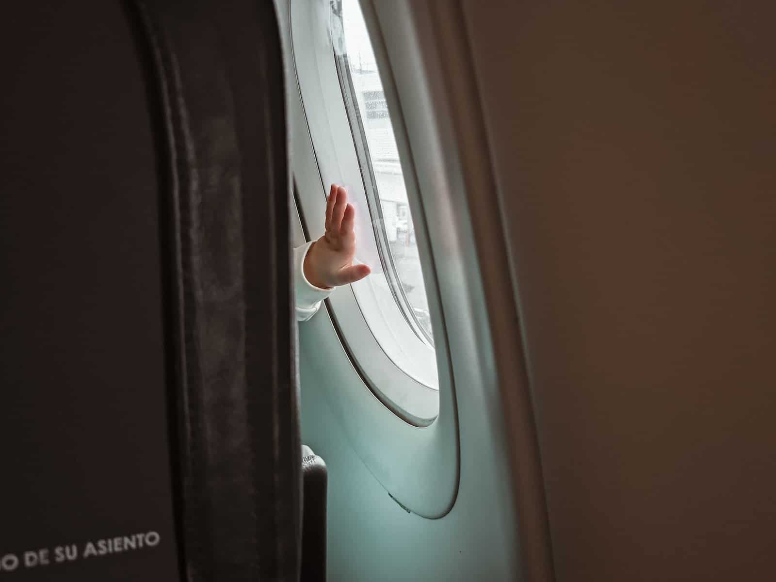 baby putting hand on airplane window