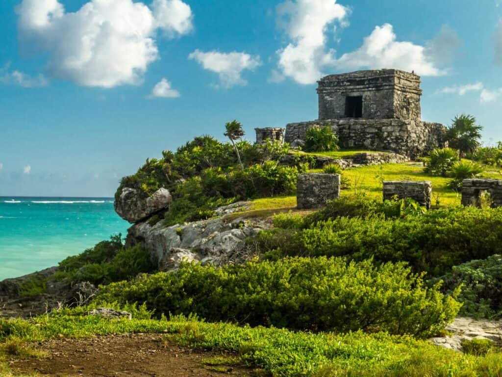 mexican pyramid ruin on a grassy hill overlooking the ocean
