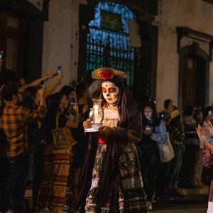 mexican woman calavera makeup holding candle on dia de los muertos