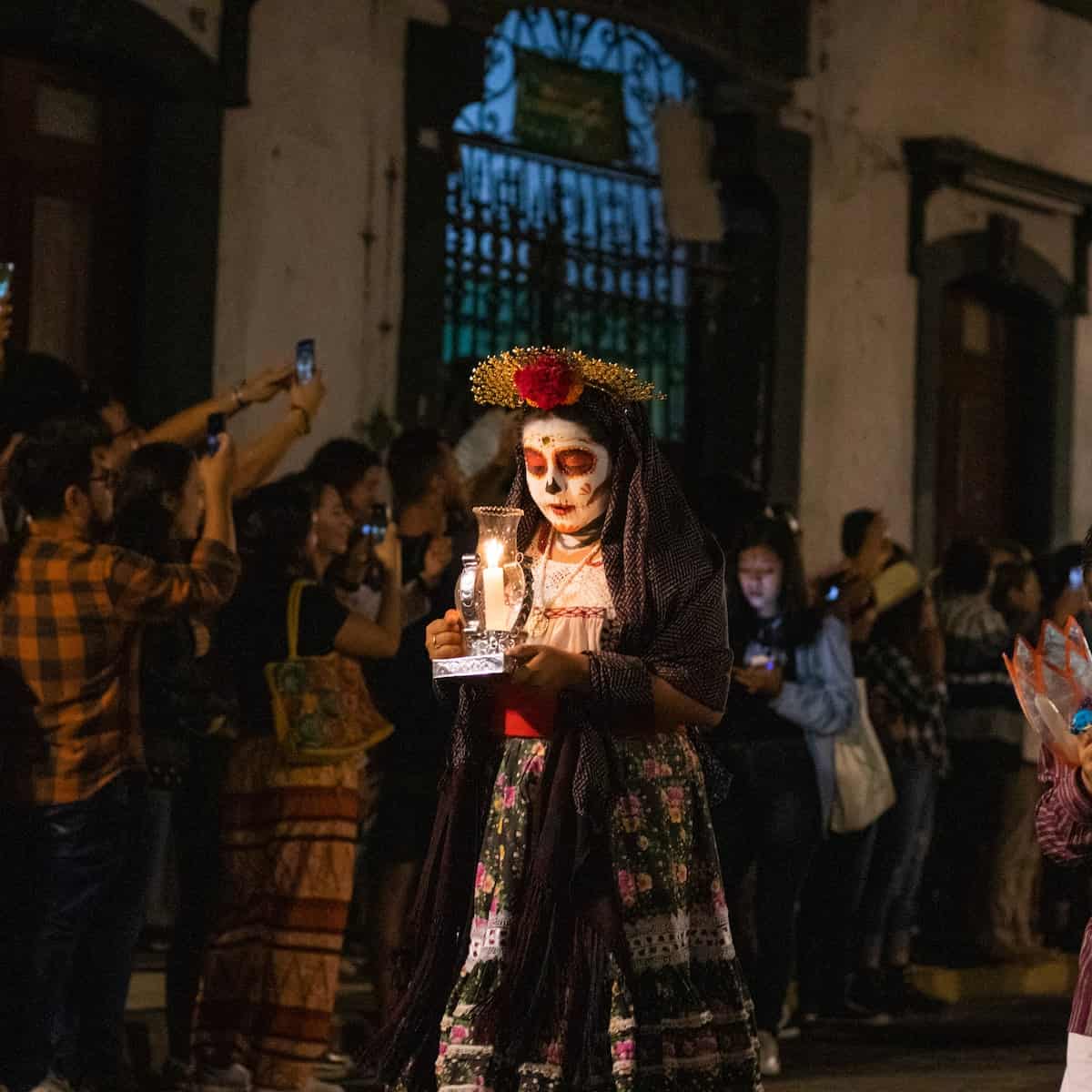 mexican woman calavera makeup holding candle on dia de los muertos