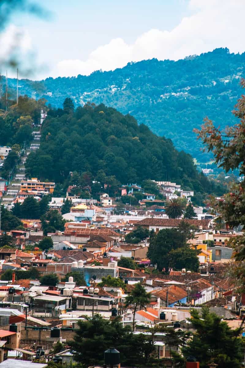 aerial view of green trees and houses in mexican town of San cristobal near mountain during daytime