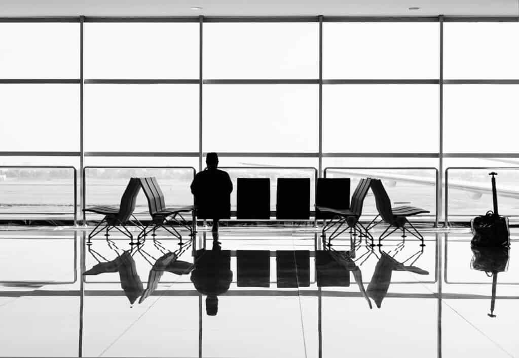 black and white man sitting on airport chair during daytime