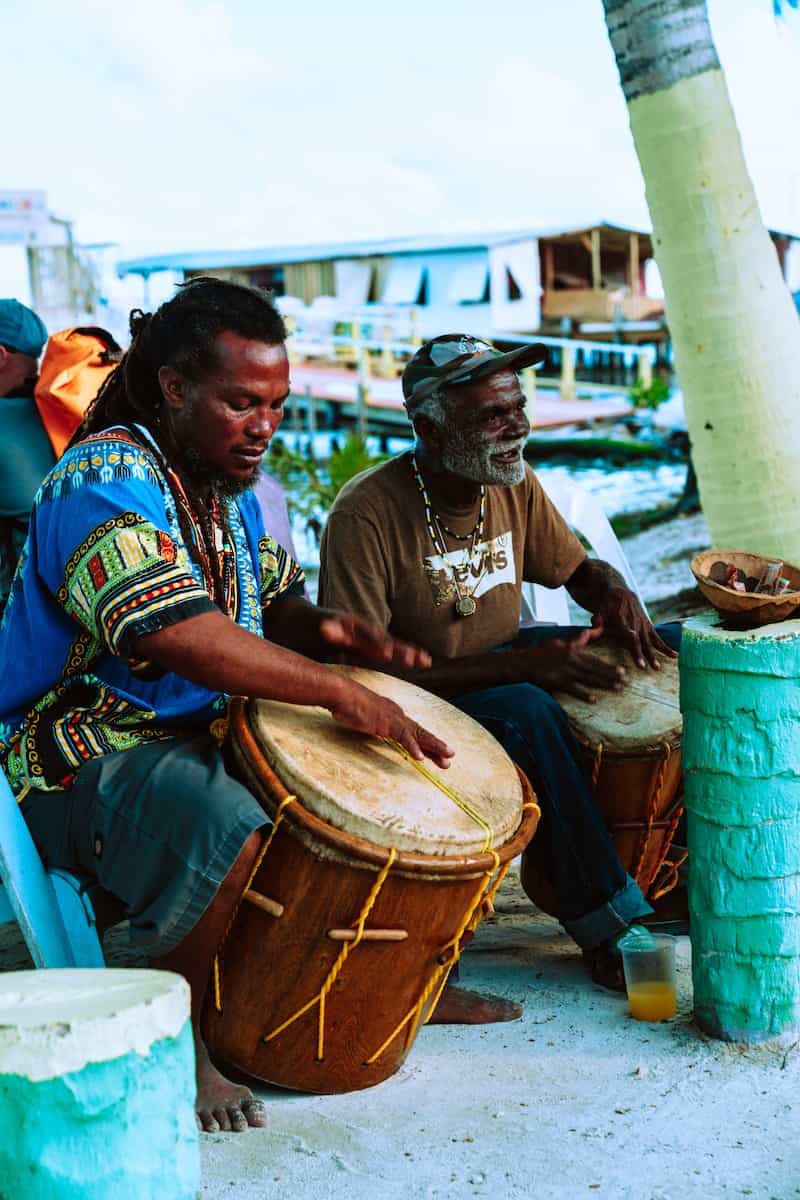 two men playing beach drum in belize