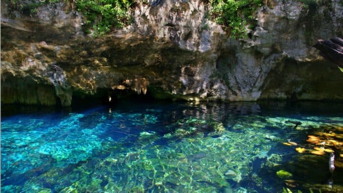 sunlight shining through gorgeous crystal clear blue cenote water in a cave
