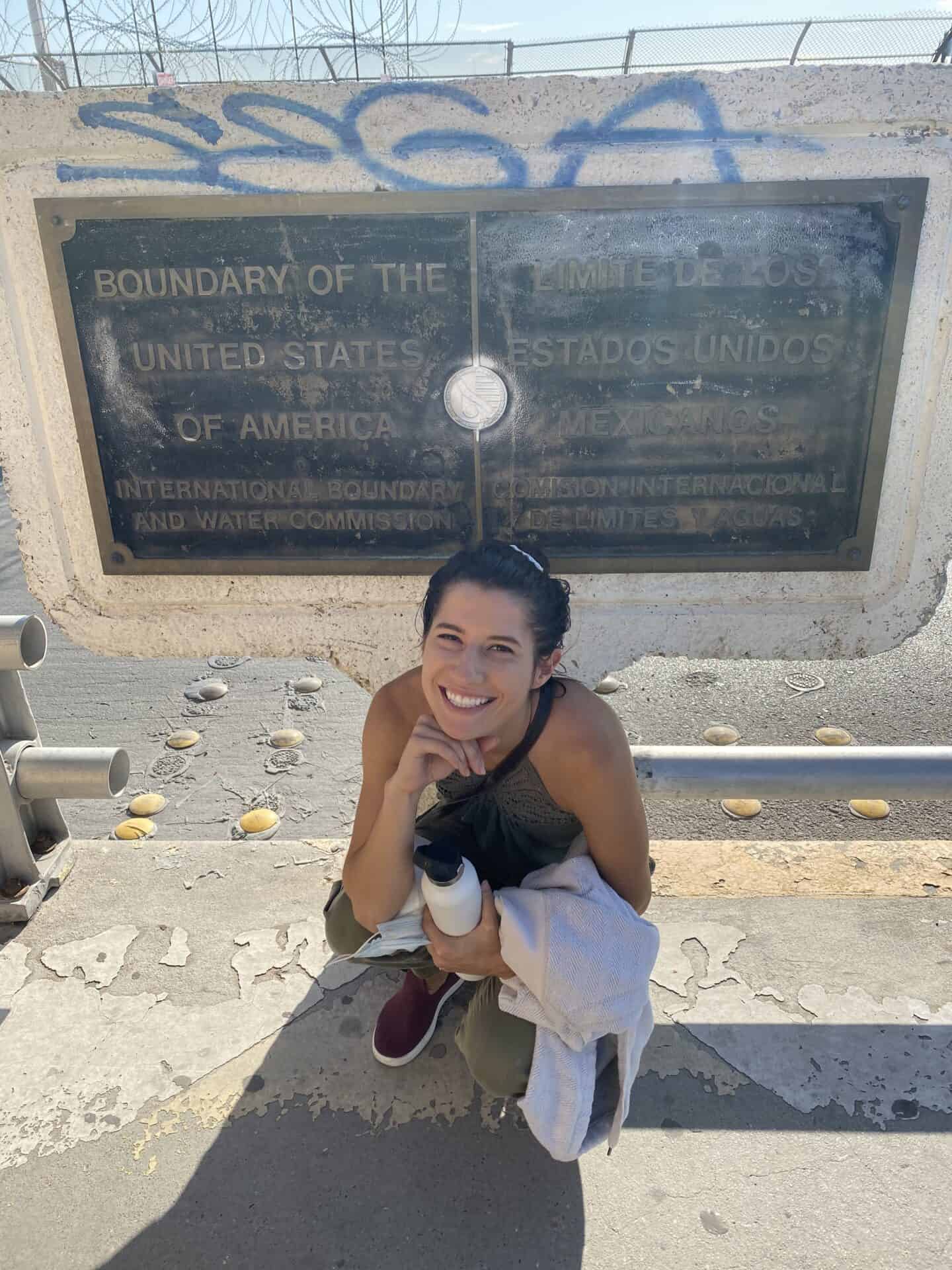 woman sitting under plaque at El Paso Juarez Border Crossing Paso del Norte Bridge