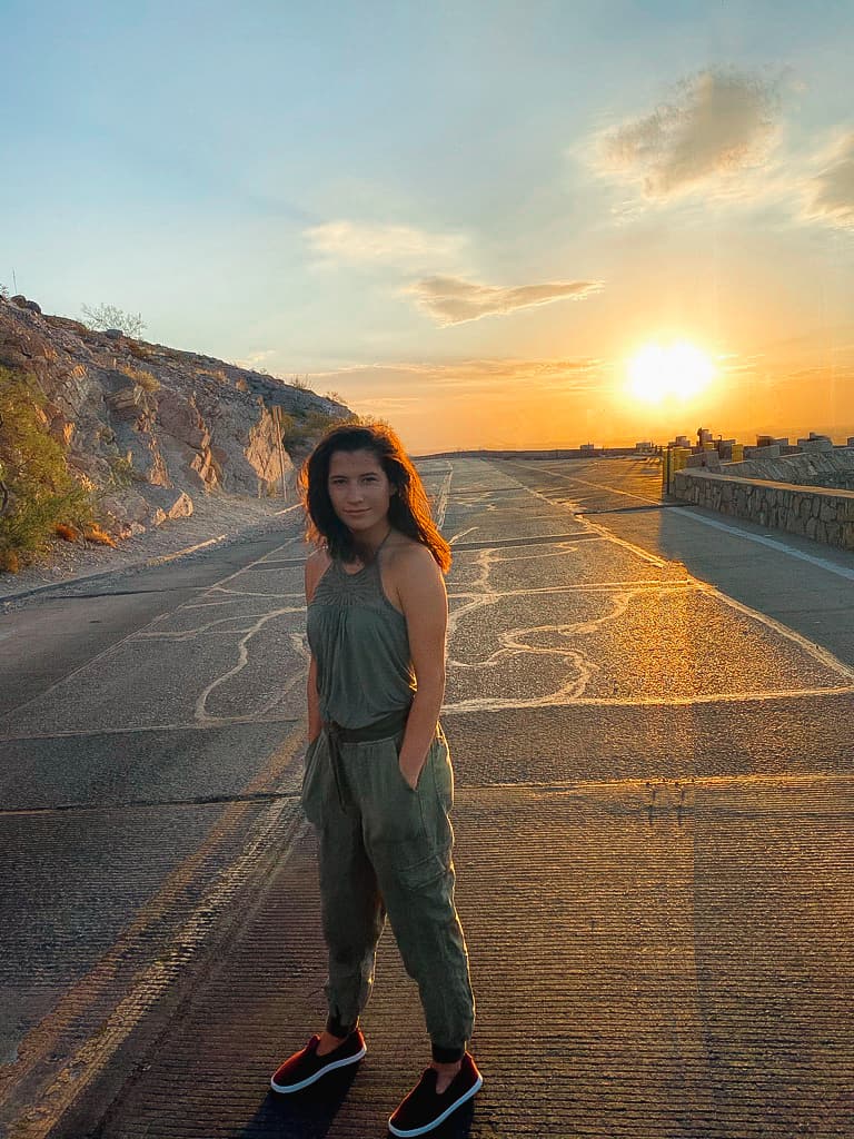 woman in green top standing on road during soft sunrise