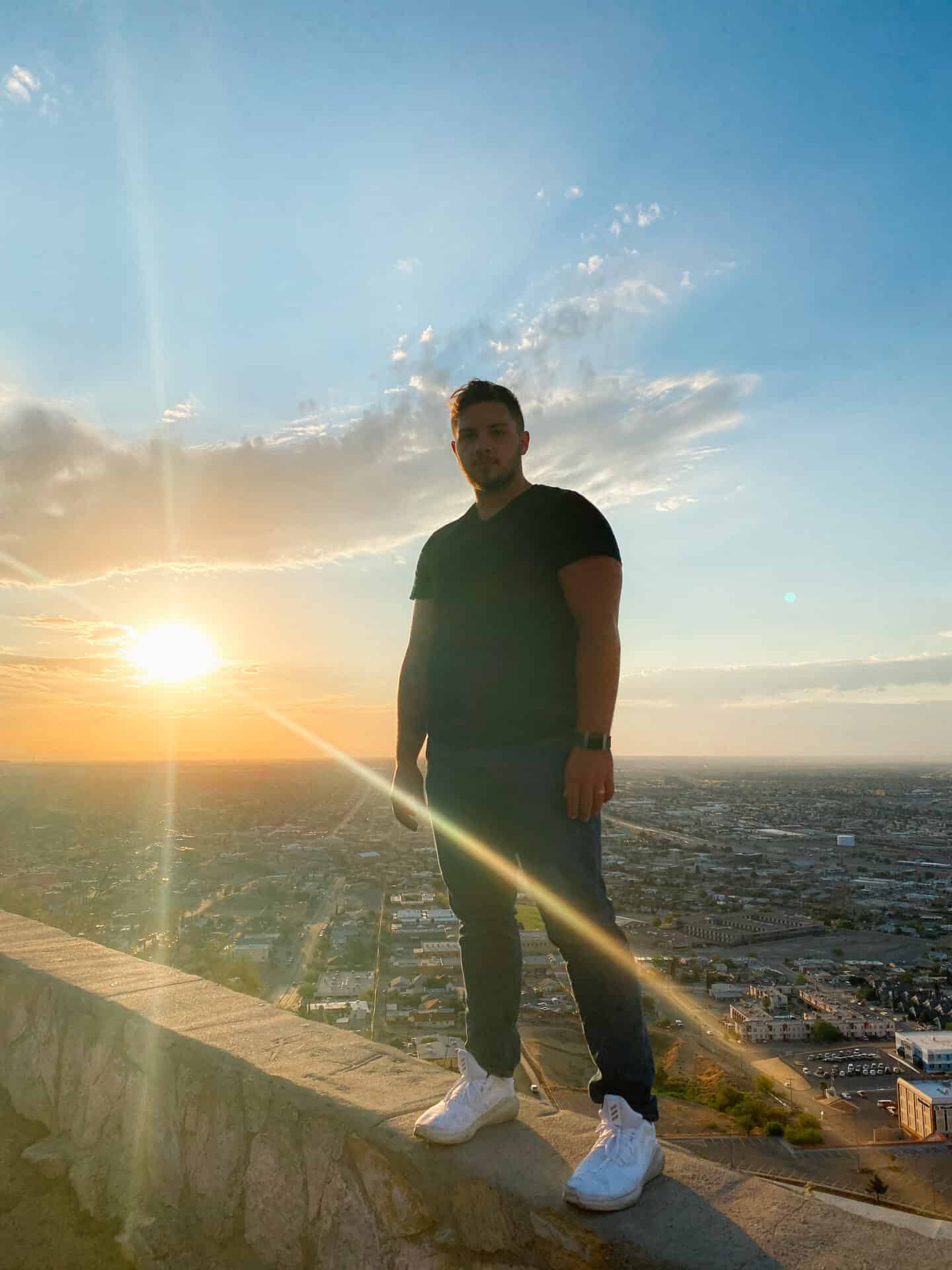 man standing on wall overlooking El Paso at sunset