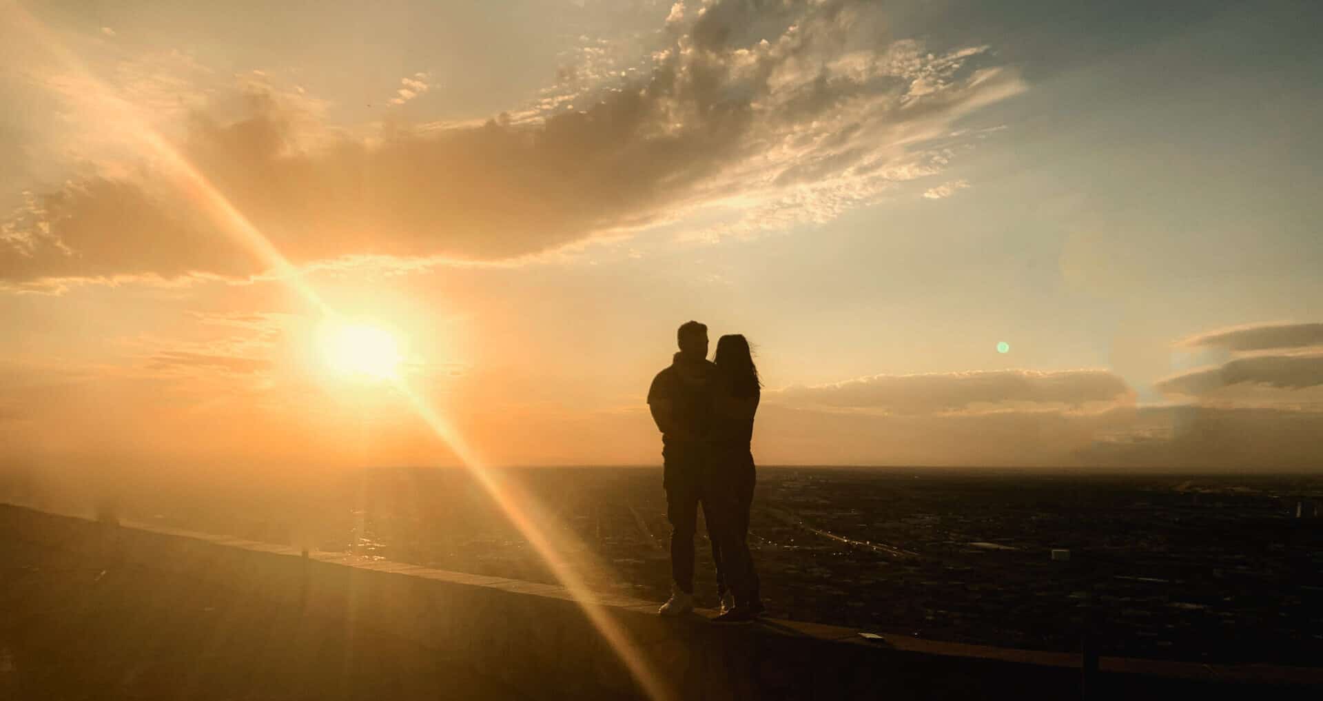 silhouette of couple embracing on wall overlooking El Paso at sunset