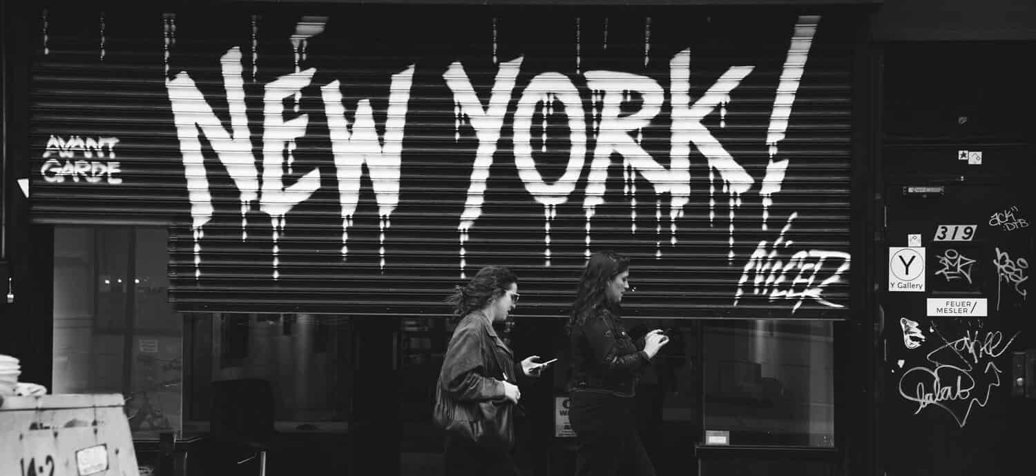 People in front of black garage door with New York Graffiti in white