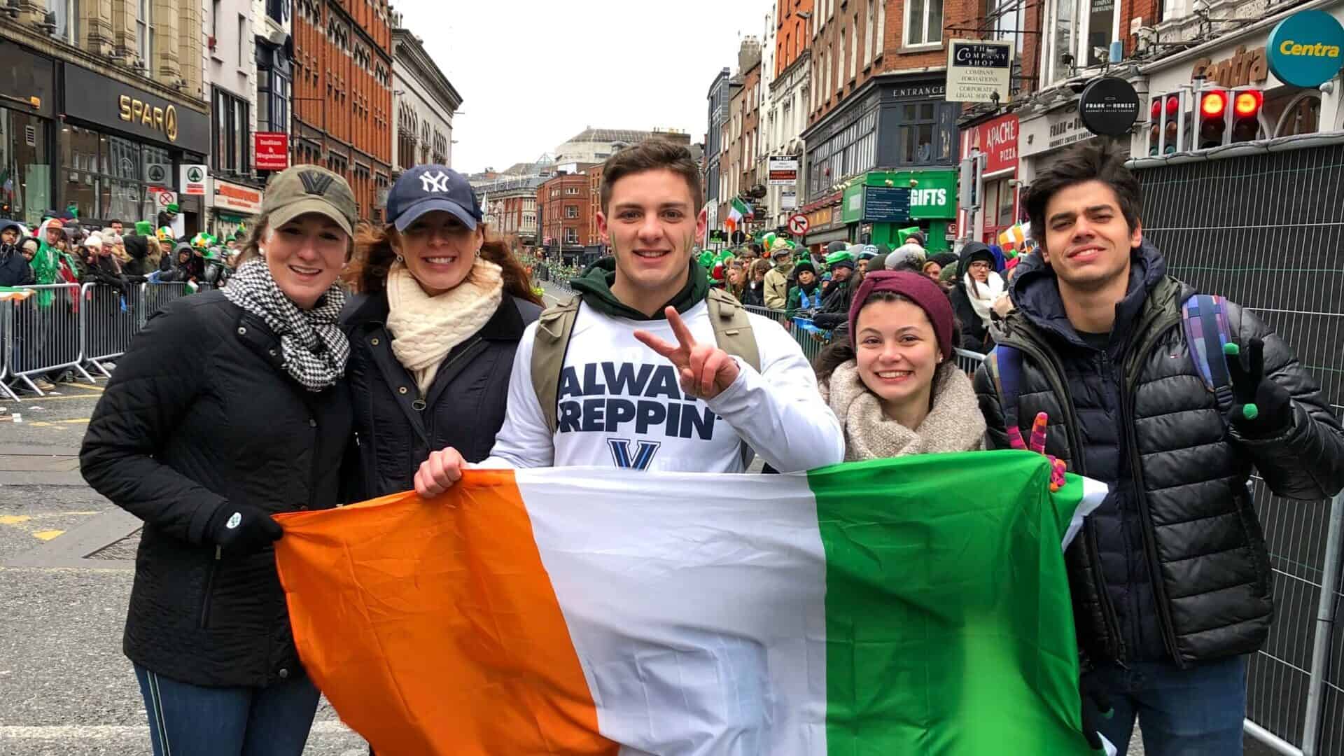 group of college students holding irish flag at st patricks day parade in ireland