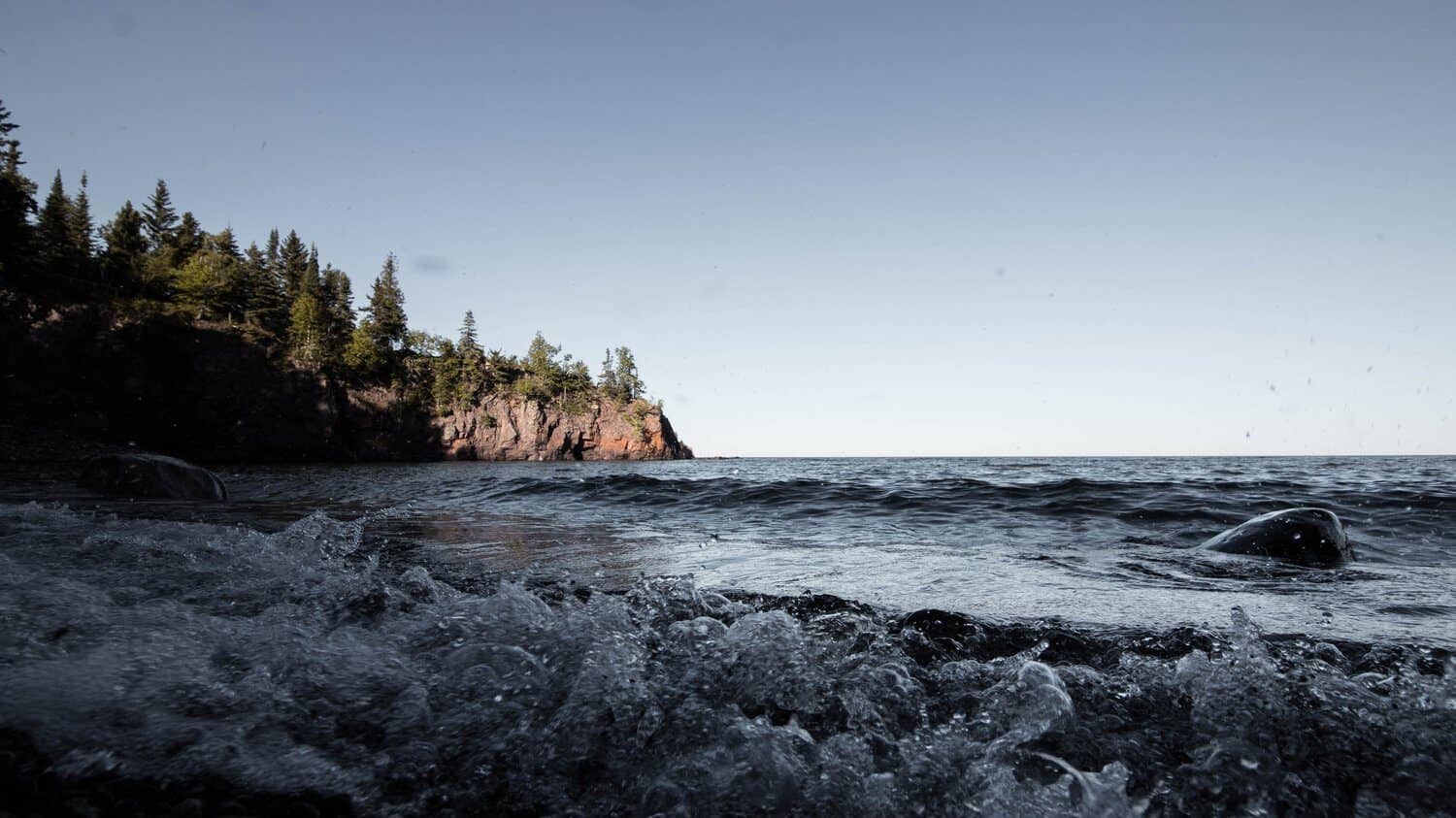 image of dark ocean waves crashing into rocky shore