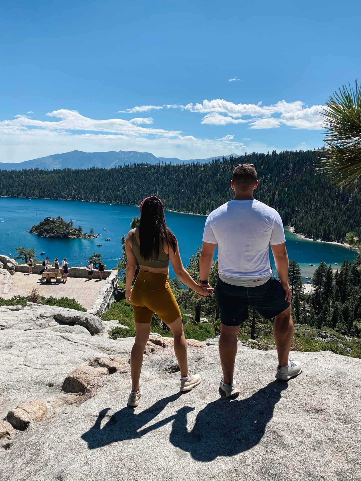 man and woman holding hands while looking at clear blue lake tahoe