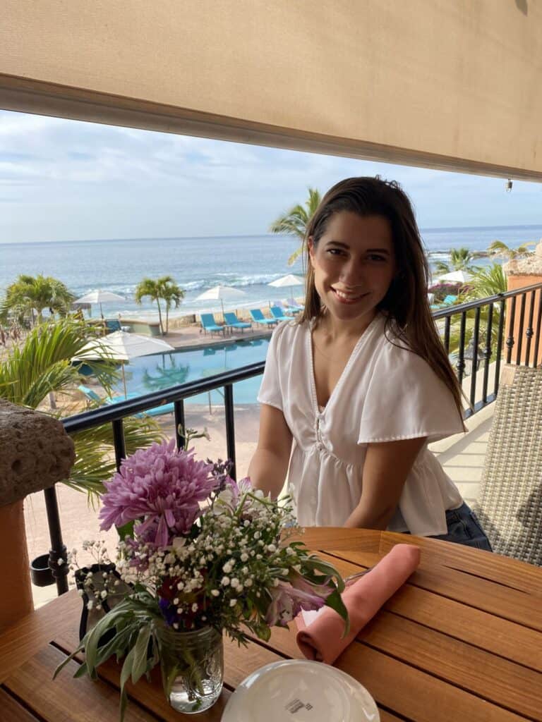 woman in white blouse sitting in restaurant overlooking the ocean