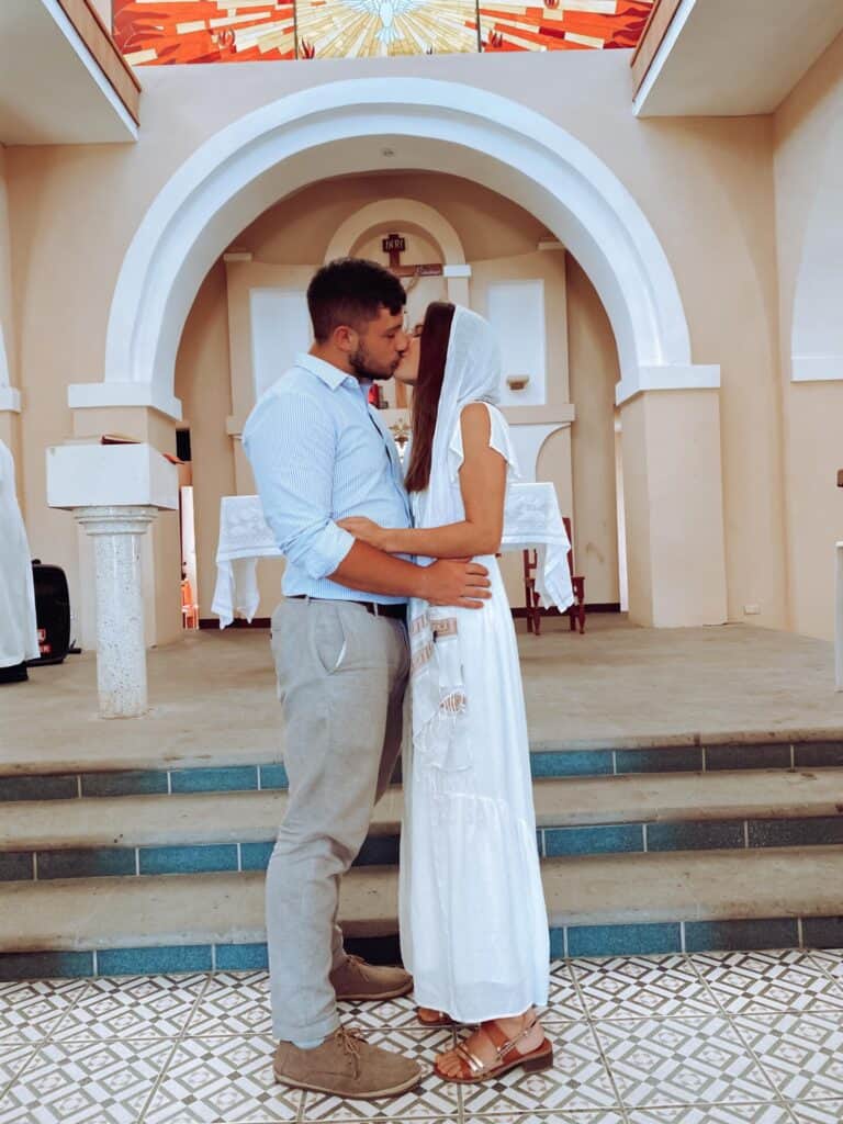 husband and wife with veil kissing inside catholic church