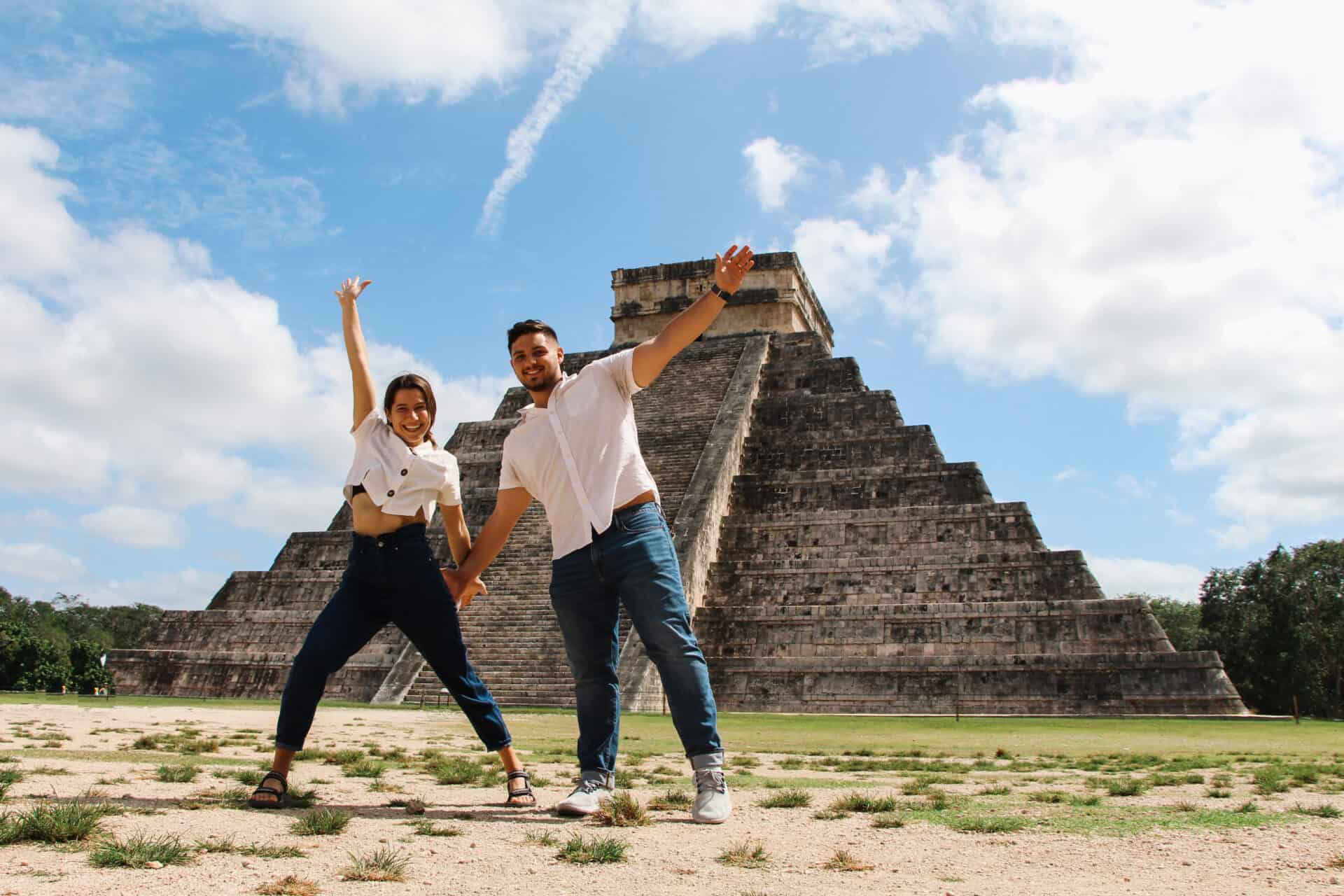 couple in blue jeans and white shirts celebrating at chichenitza pyramid in mexico