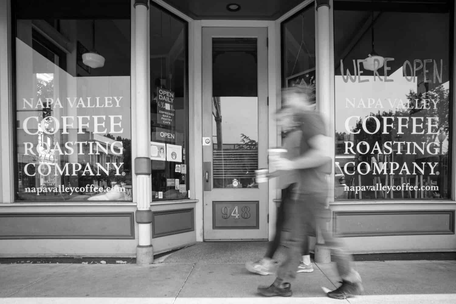 black and white photo of Pedestrians walking in front of coffee shop