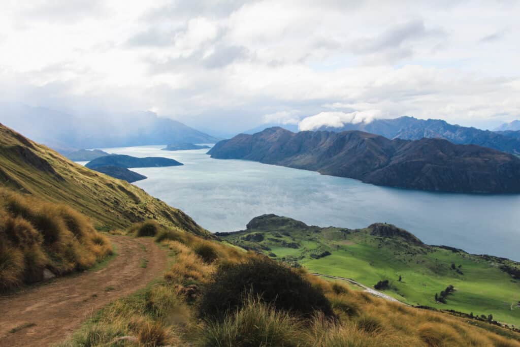 gorgeous lake, green pastures, and blue mountains in New Zealand Roys Peak