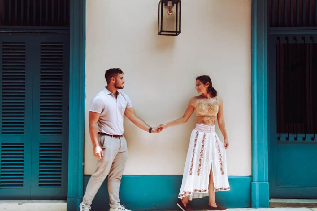 woman and man holding hands by a white and blue street wall in panama city