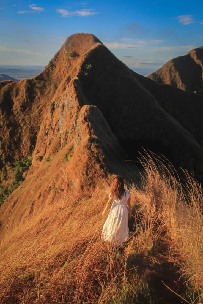 woman in white dress standing on gorgeous mountain range during sunrise