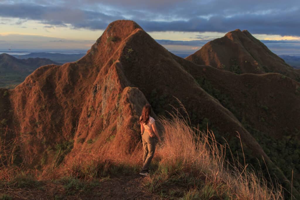 woman standing on gorgeous mountain range during sunrise
