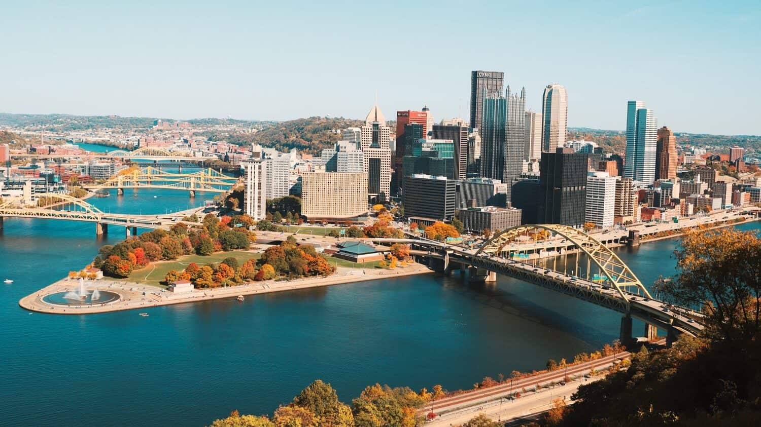 drone shot view of pittsburgh city and river under blue sky