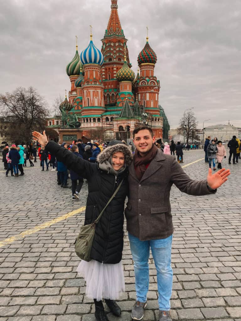 man and woman in winter jackets standing in front of main church in moscow