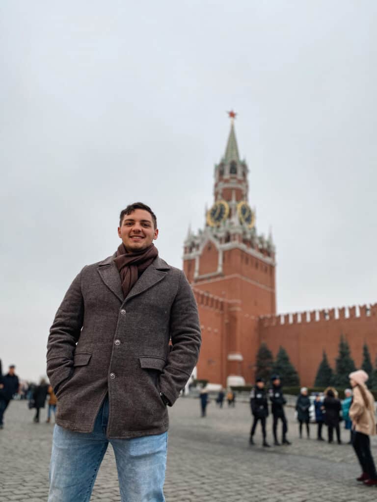 man standing in front of the red Kremlin in russia square
