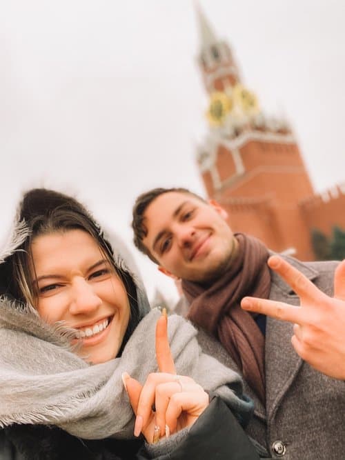 selfie of man and woman pointing to the Kremlin in Moscow