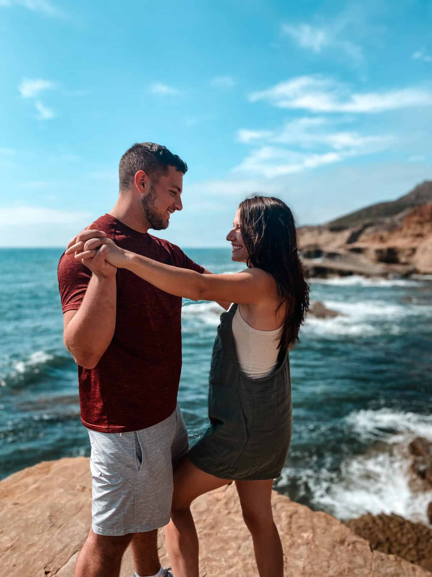 couple embracing on San Diego tidal pool rocks overlooking ocean with crashing waves