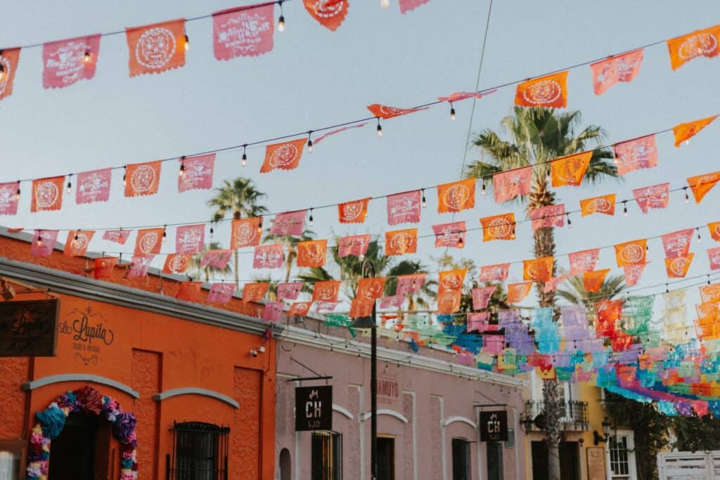 colorful mexican town buildings with colorful flag decorations stringing across street