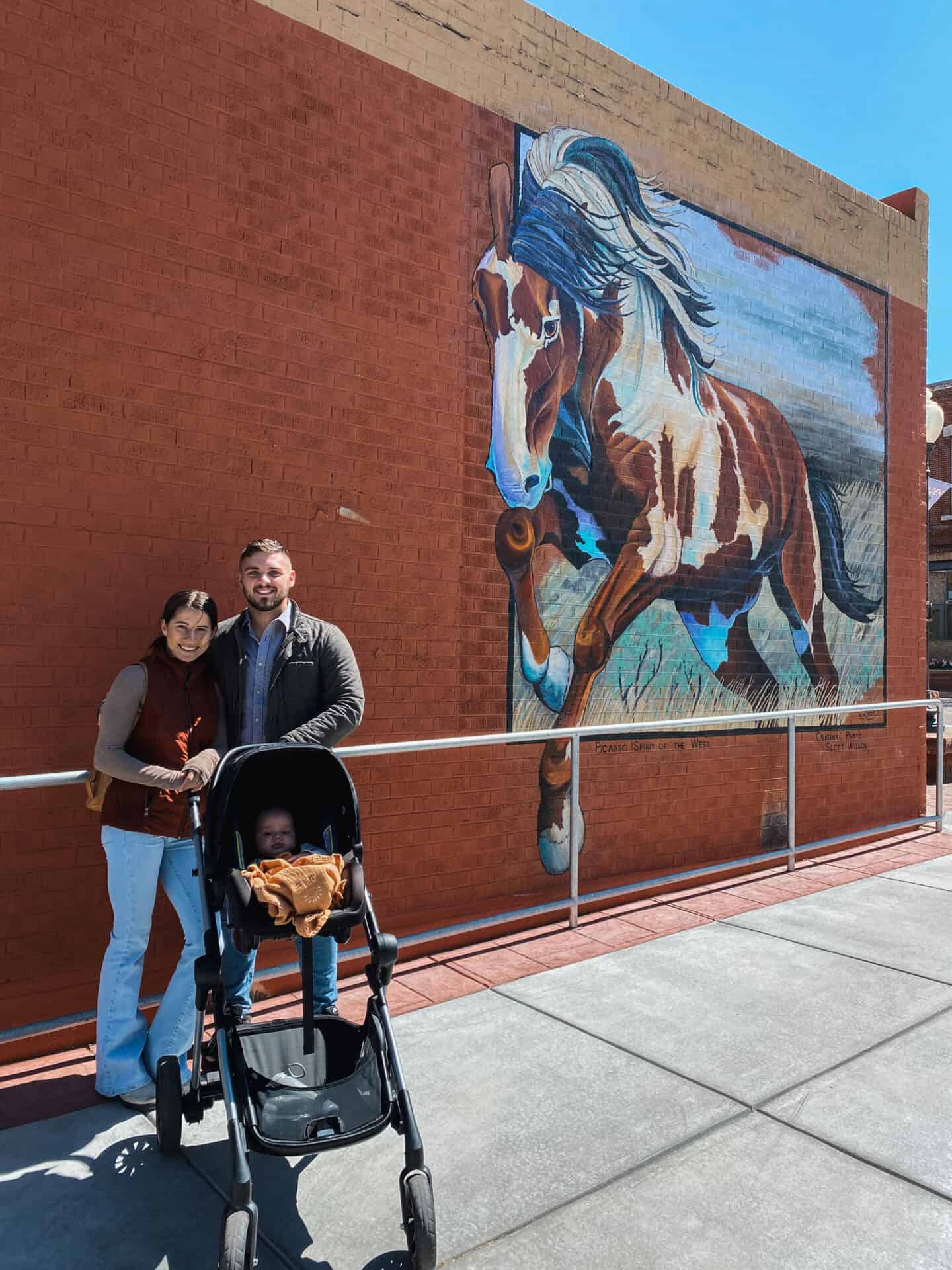 family with stroller in front of wild stallion mural in Golden Colorado