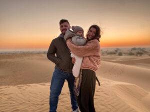 man and woman travel couple holding their toddler sun in the great indian desert during sunrise