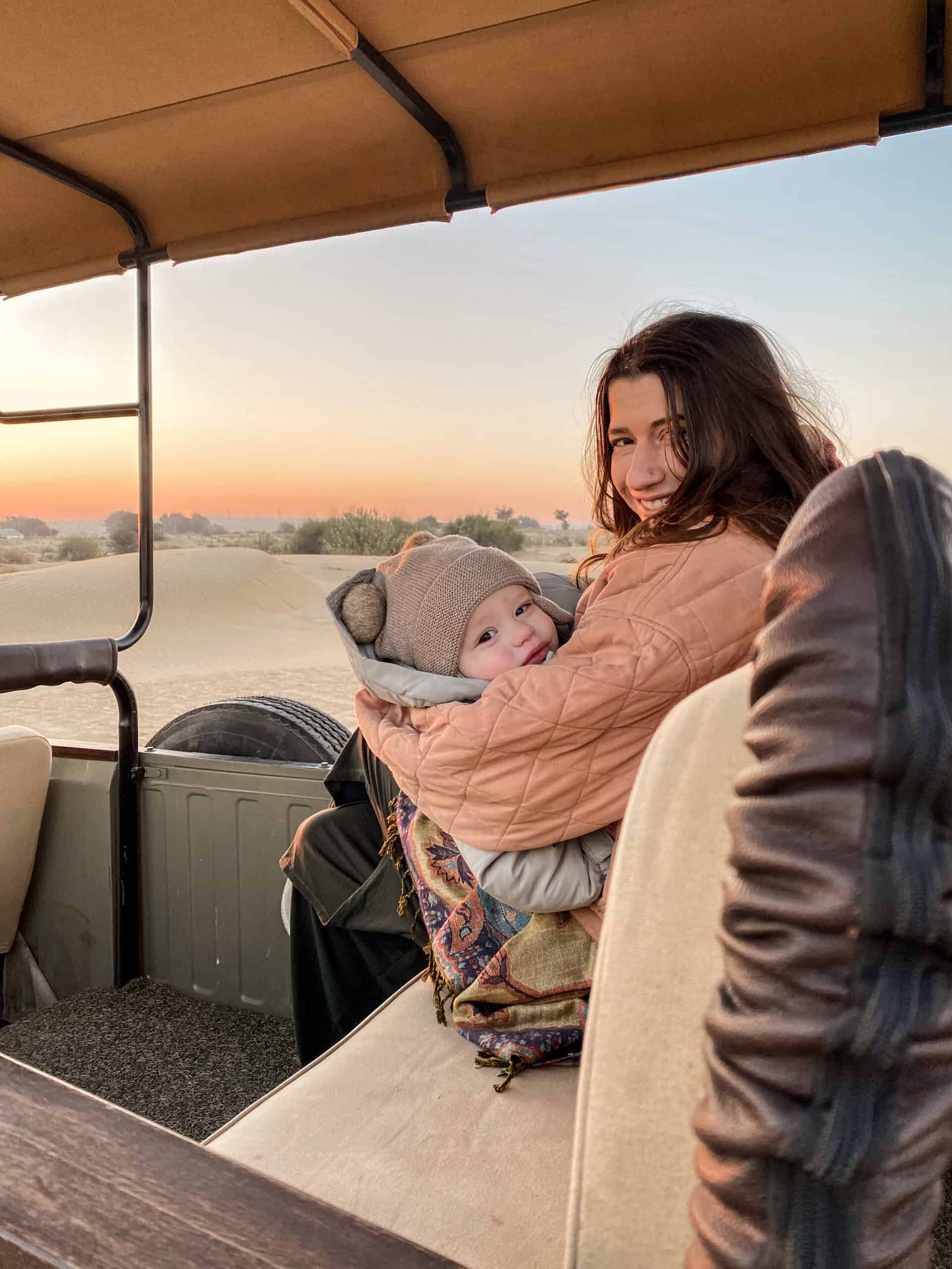 mother cradling her baby on a Jeep Safari in Desert at Sunrise