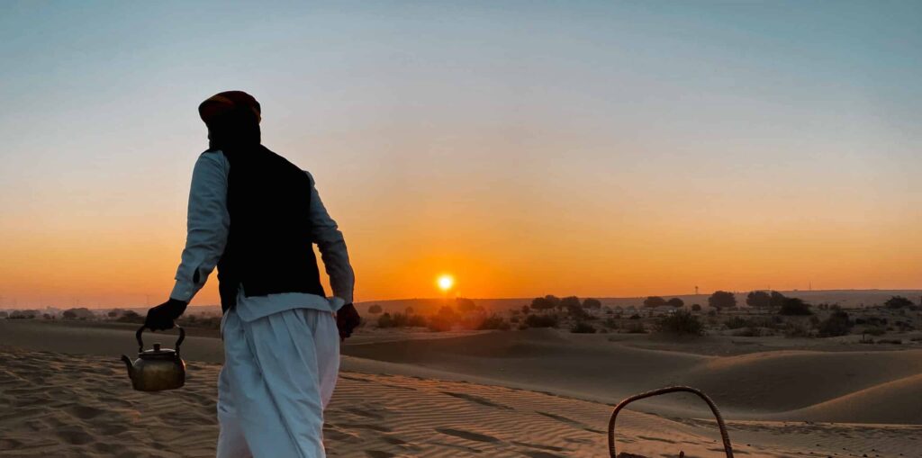 man serving tea in the great thar desert during sunrise