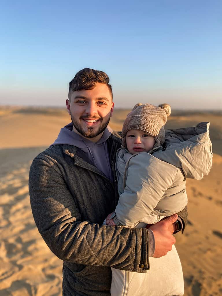 father holding son who is bundled in winter clothing in the great indian desert