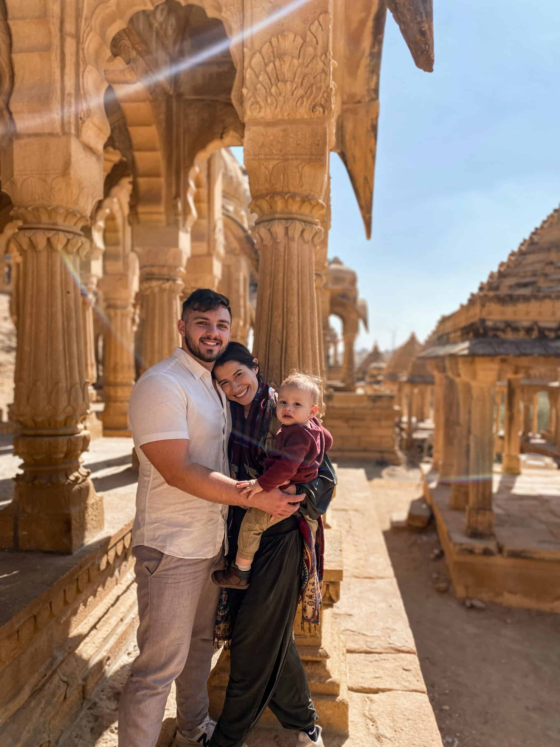 cute travel couple holding their toddler son in magnificent hindu temple