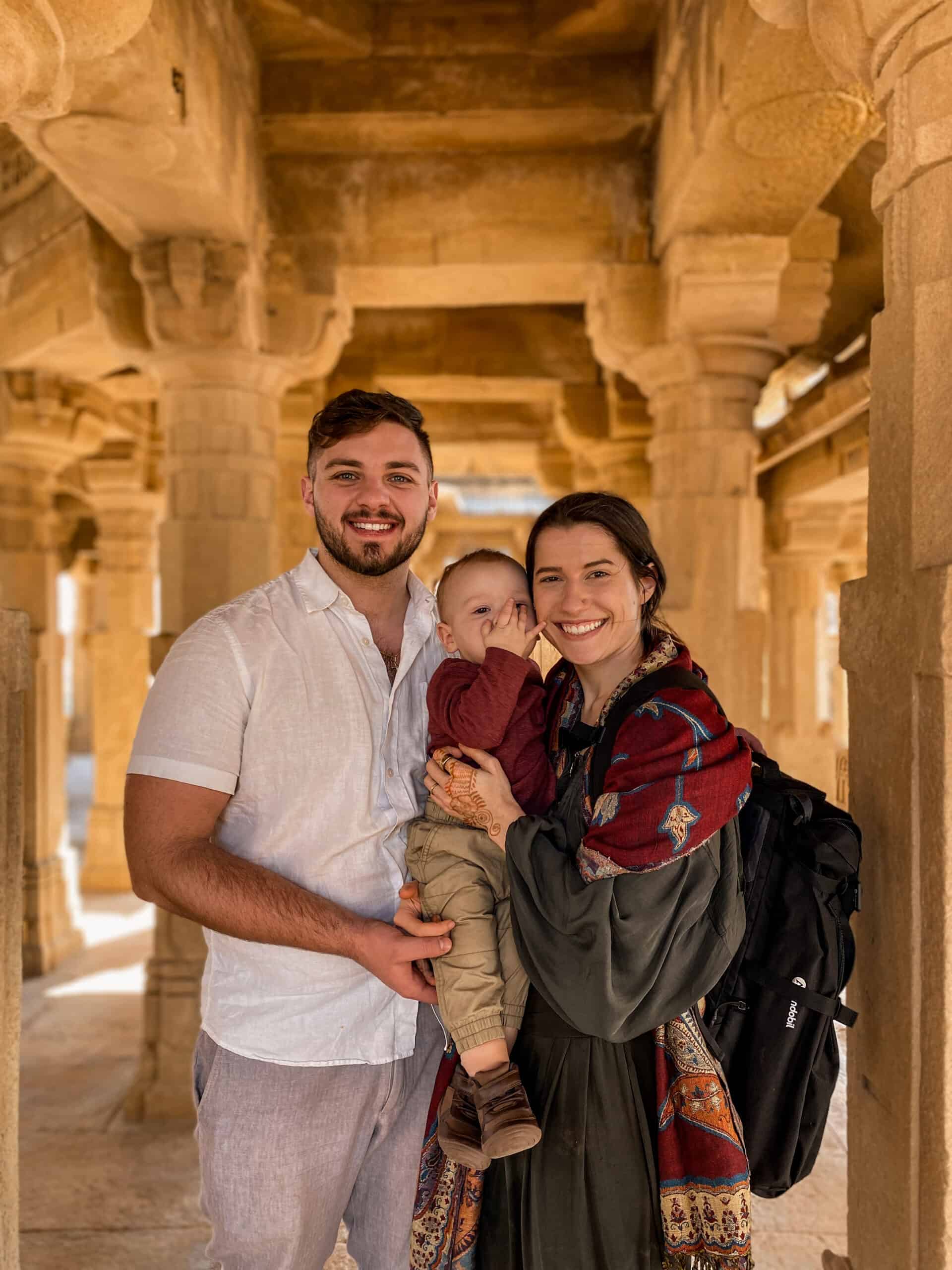 cute travel couple holding their toddler son in magnificent hindu temple
